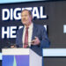 Dr. J. Patrick Johnson speaking from a podium at the Digital Health Forum during the Global Health Exhibition in Riyadh, Saudi Arabia.